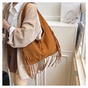 Detailed view of long fringes on a vintage brown suede oversized hobo shoulder bag