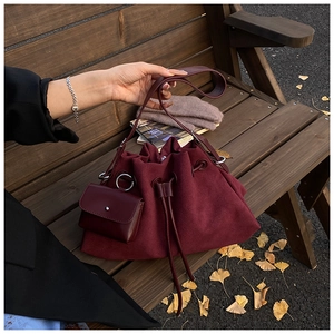 Close-up of vintage burgundy suede bucket bag with drawstring and small square pouch pendant