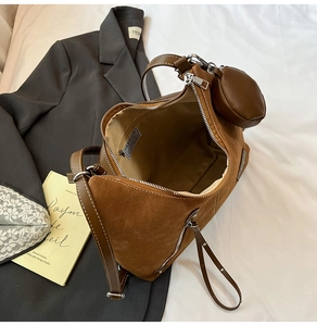 Detail view of brown suede tote bag with zipper and small round hanging coin purse