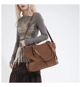 Detail of leopard print suede tote bag featuring brown leather handles and gold ring hardware