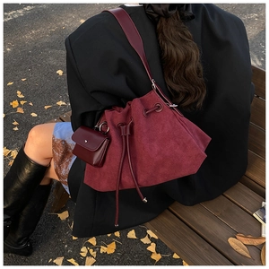 Dettaglio borsa a secchiello bordeaux in camoscio con coulisse e mini pochette coordinata