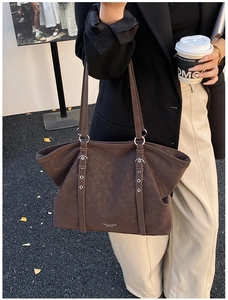 Detail of dark brown faux leather tote bag featuring decorative long straps and silver rings