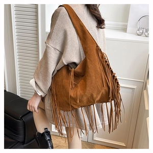 Close-up of bohemian brown suede tote bag with long tassels and wide shoulder strap detail