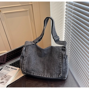 Dettaglio della borsa messenger in denim grigio scuro con tracolla regolabile in ufficio