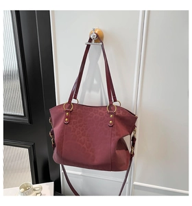 Close-up of deep burgundy leopard print tote bag with gold ring hardware and matte finish