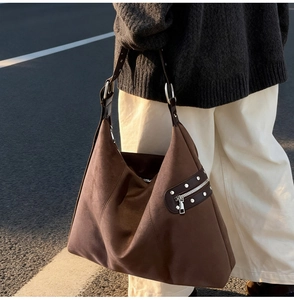 Close-up of hobo shoulder bag featuring coffee suede texture and silver rivet details