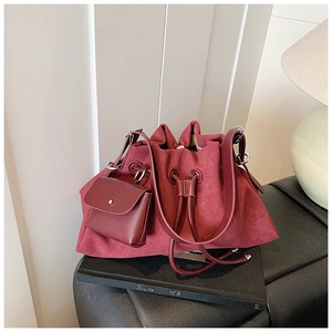 Detail of burgundy suede tote bag with drawstring closure and mini matching pouch charm