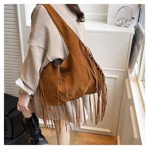 Macro detail of brown suede tote bag featuring long bohemian tassels and vintage texture