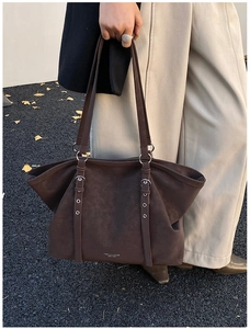 Detail of dark brown leather tote bag showing buckle straps and brand logo embossing