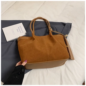 Détail du sac cabas en daim marron avec base en cuir lisse et pendentifs à franges