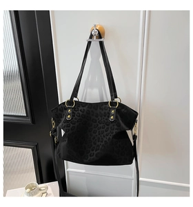 Detailed close-up of black leopard print tote bag with gold ring hardware and thin handles