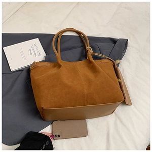 Vue de dessus d'un grand sac cabas en daim marron avec détails de franges sur tissu blanc