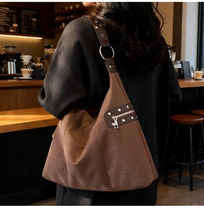 Detailed macro view of brown suede tote bag with studded strap and metal ring attachment