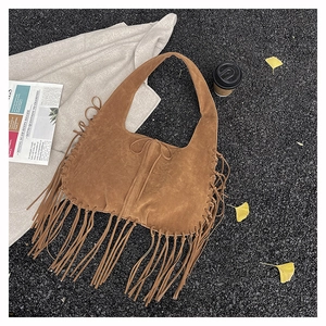 Detail of bohemian brown suede tote bag featuring braided side straps and long tassels