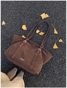 Detail of dark brown leather tote bag on asphalt background with yellow ginkgo leaves