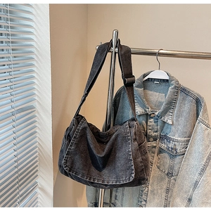 Dettaglio della tracolla larga regolabile e della fibbia in metallo della borsa in denim