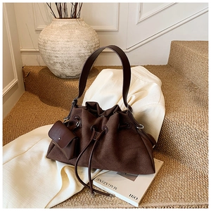 Detail of dark brown drawstring bucket bag with matching coin purse on textured stairs