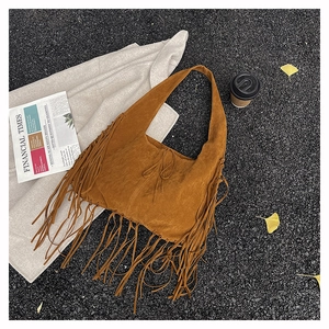 Flat lay of brown suede fringe tote bag with street style props on grey asphalt