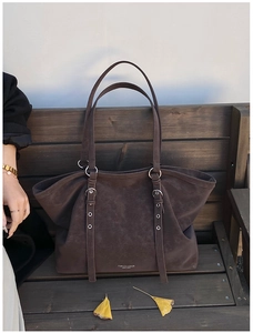 Detailed macro view of dark brown frosted leather tote bag with sturdy metal buckles
