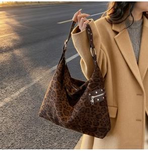 Close-up of leopard print shoulder bag with metallic rivets and adjustable strap details