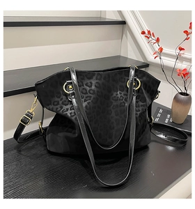 Detail of black leopard print texture and gold metal ring handle on tote bag
