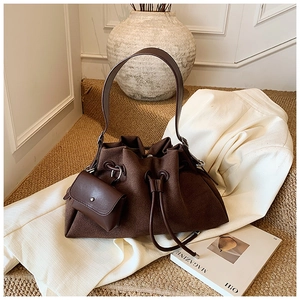Detail of dark brown suede bucket bag with drawstring closure and small pouch accessory
