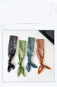 Détail de quatre foulards en soie floraux noués à un sac en cuir noir en diverses couleurs