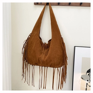 Close-up of brown suede hobo bag with long fringes and drawstring detail in home setting