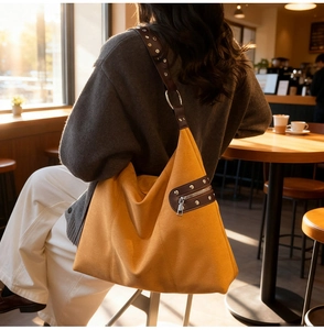 Detail of ginger suede tote bag with brown leather accents and metallic rivets