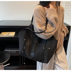 Détail du grand sac cabas noir avec cordons de serrage et patch logo sur modèle