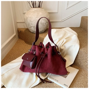 Detail of burgundy suede bucket bag and mini pouch placed on steps in lifestyle setting