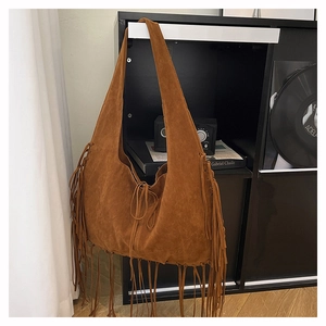 Macro detail of brown suede tote bag featuring long fringes and bohemian styling