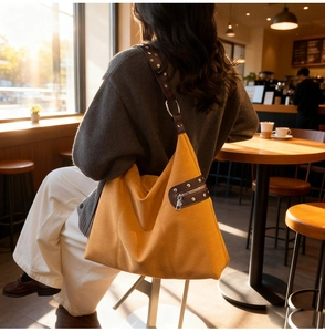 Close-up of ginger canvas tote bag with brown leather straps and metal rivets detail