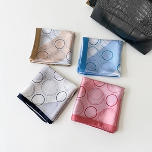Detail of silk-like square scarves with geometric ring prints and smooth drape texture