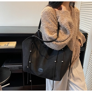 Détail du sac cabas noir avec cordons de serrage à pompons et perles métalliques argent
