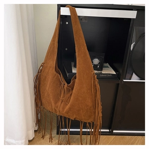 Close-up of brown suede tote bag featuring bohemian long fringe and leather drawstring