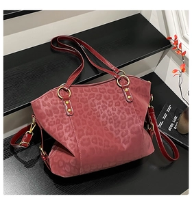 Detail of red faux leather tote bag showing leopard embossed texture and gold hardware