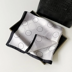 Detailed view of polka dot silk scarf tied on black crocodile leather texture handbag