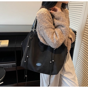 Détail du grand sac cabas noir mat avec de fines lanières en cuir et des perles en métal