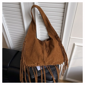 Close-up of brown suede fringe tote bag featuring bohemian tassels and drawstring ties