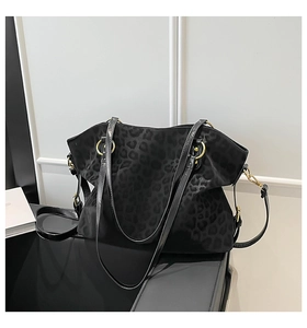 Close-up of black leopard print suede tote bag with gold ring hardware and handles