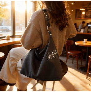 Detail of black faux suede tote bag with silver studs and decorative side zipper pocket