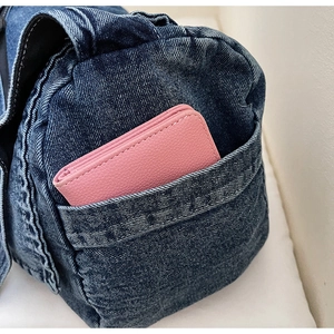 Dettaglio della tasca laterale in denim blu con portafoglio in pelle rosa e cuciture
