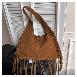 Detailed close-up of brown suede tote bag with long fringes and bohemian style tie closure