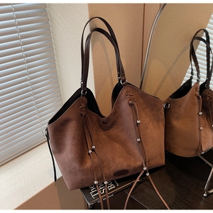 Détail du grand sac cabas en daim marron foncé avec pompons et perles argentées élégants