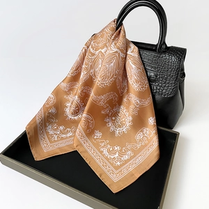 Détail d'un foulard en soie à motif cachemire noué sur le manche d'un sac à main en cuir
