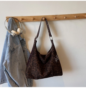 Detail view of large leopard print tote bag featuring metallic eyelet shoulder strap