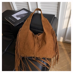 Macro view of brown suede tote bag featuring bohemian tassels and a soft matte texture