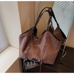 Détail du sac cabas en daim marron foncé avec de longues franges et des perles argentées