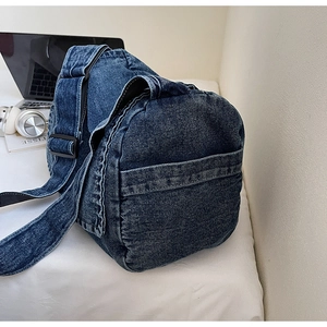 Dettaglio della borsa in denim vintage con trama lavata e ampia tracolla su sfondo bianco